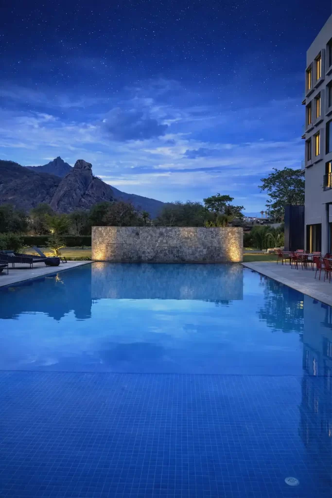 Private balcony view from a Premium Room at Avisa Hotel & Resort, overlooking manicured green lawns and the Mount Abu mountains at dusk.