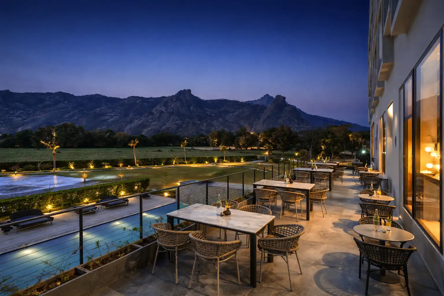 Open-air terrace restaurant at Avisa Hotel & Resort overlooking the swimming pool and illuminated lawn at night.